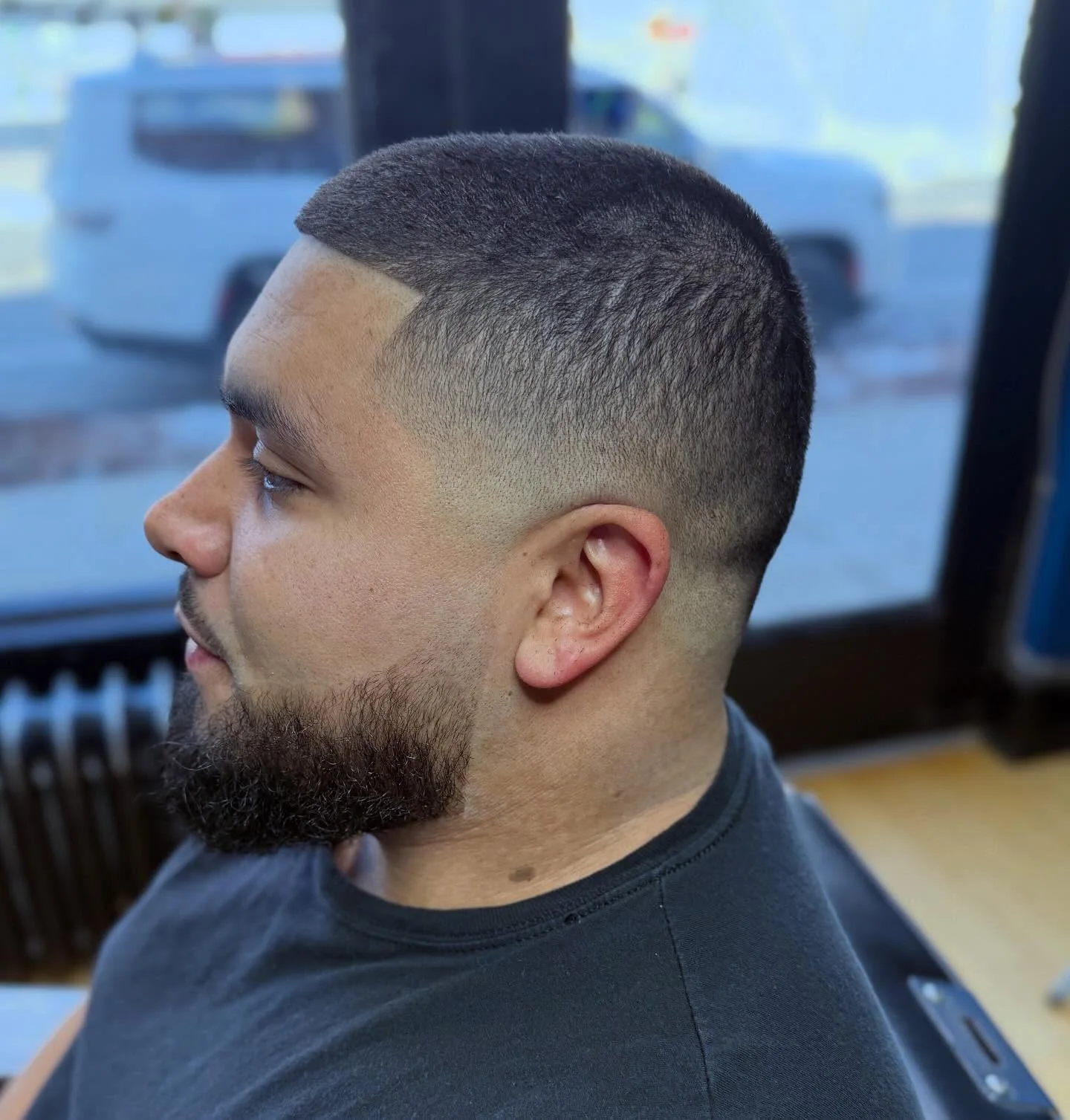 Close side view showing a smooth fade, precise front lineup, and shaped beard
