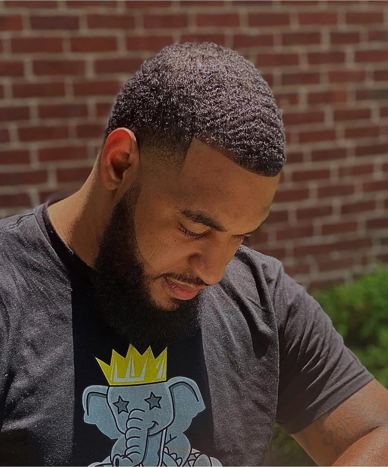 Outdoor portrait showing short waves, a crisp hairline, temple taper, and defined beard